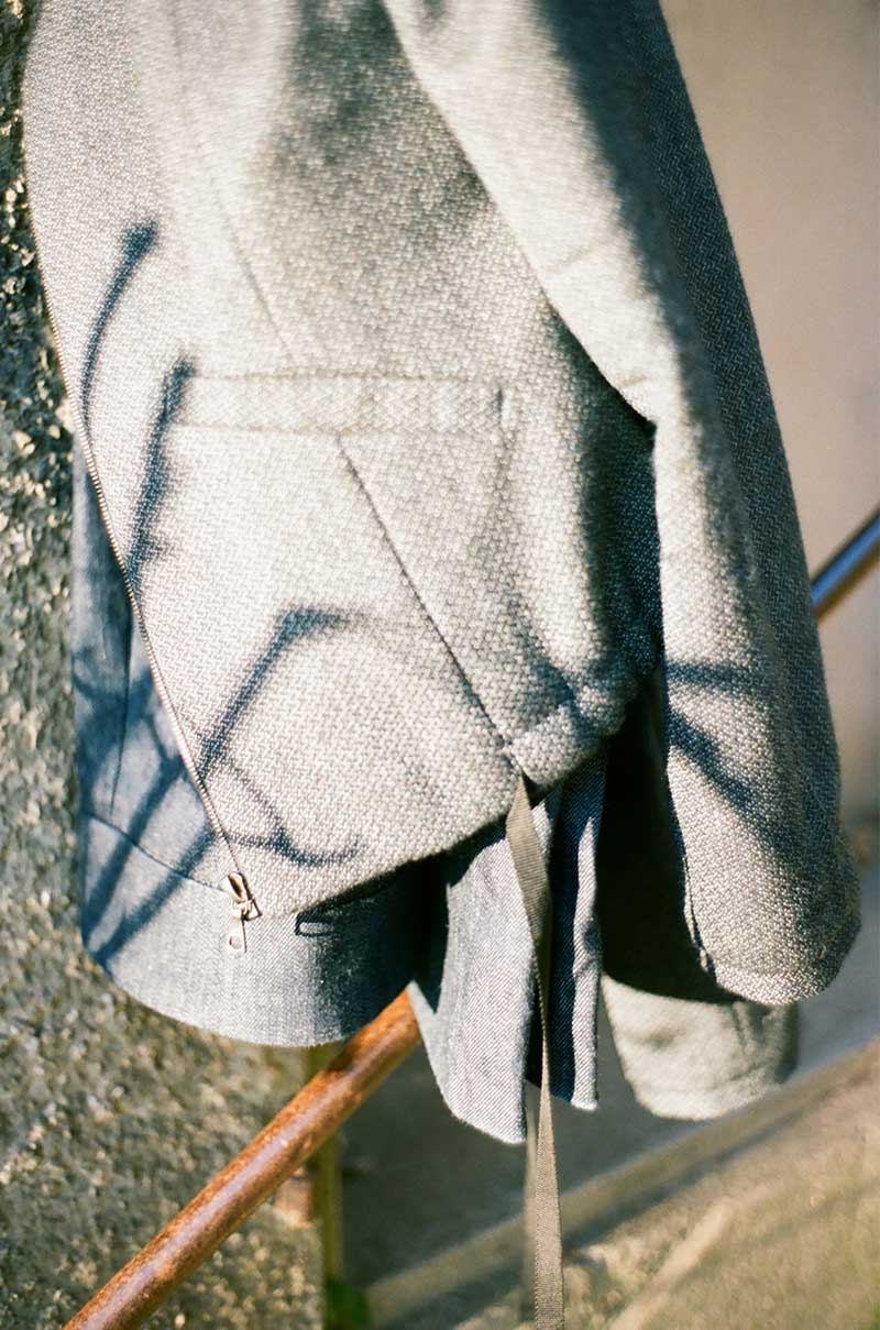 Close-up von einem grauen Jackett das von einem Schatten einer Pflanze bedeckt ist
