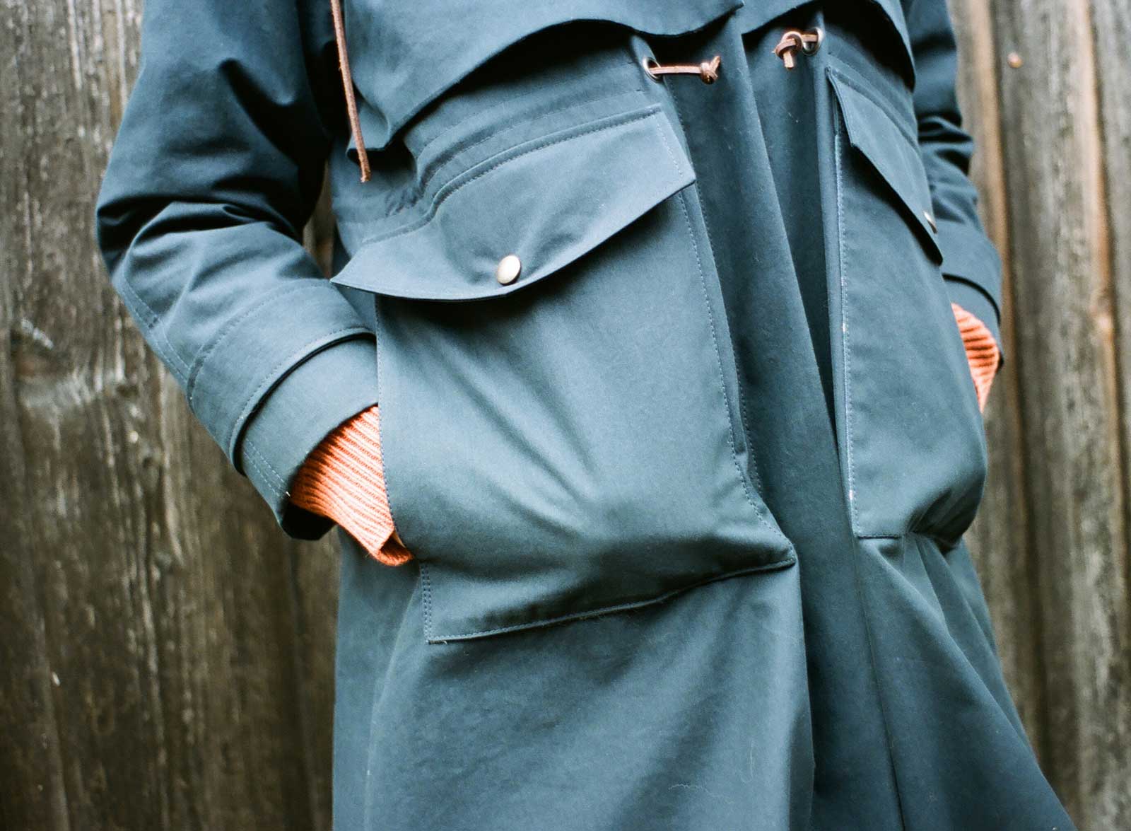 Close-up von einem blauen Herbstmantel mit Händen in den Jackentaschen