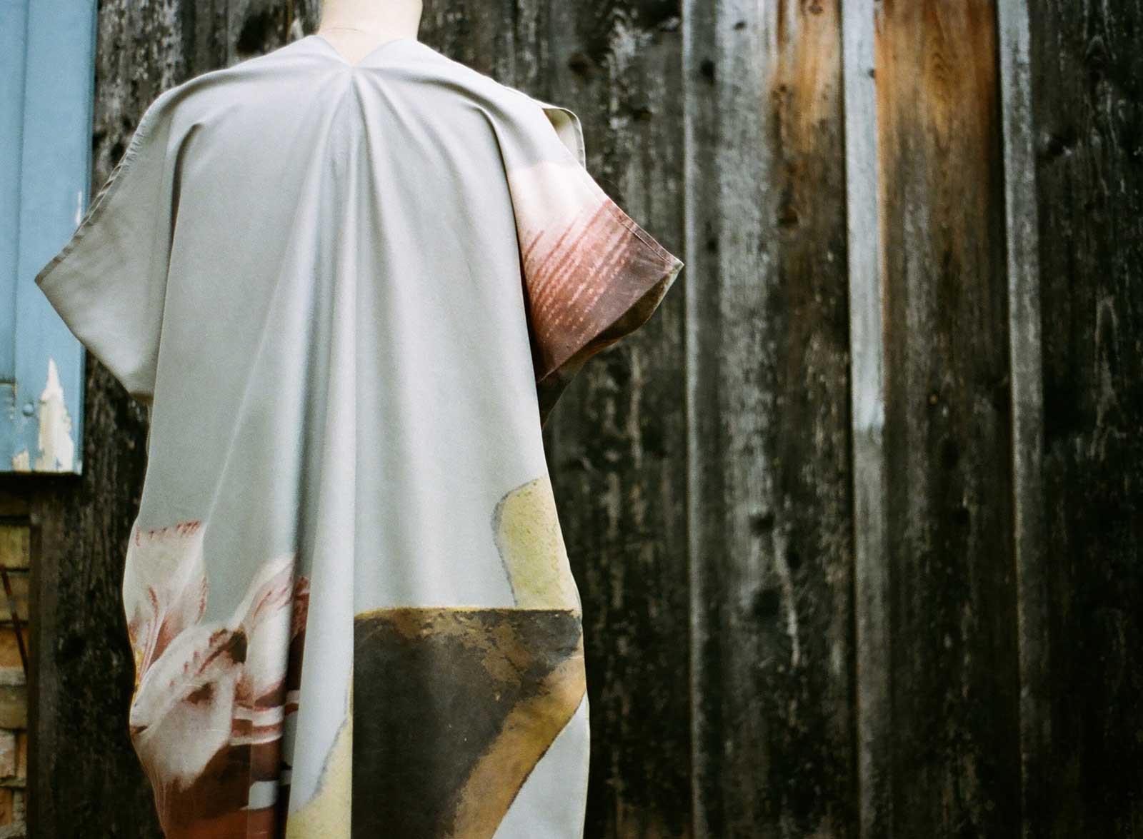 Weisses kurzärmeliges Kleid mit abstrakten Muster auf Büste vor Holzwand